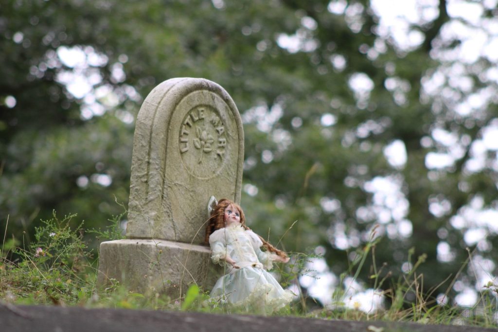 A porcelain doll placed on an old grave marker inscribed "Little Mary".